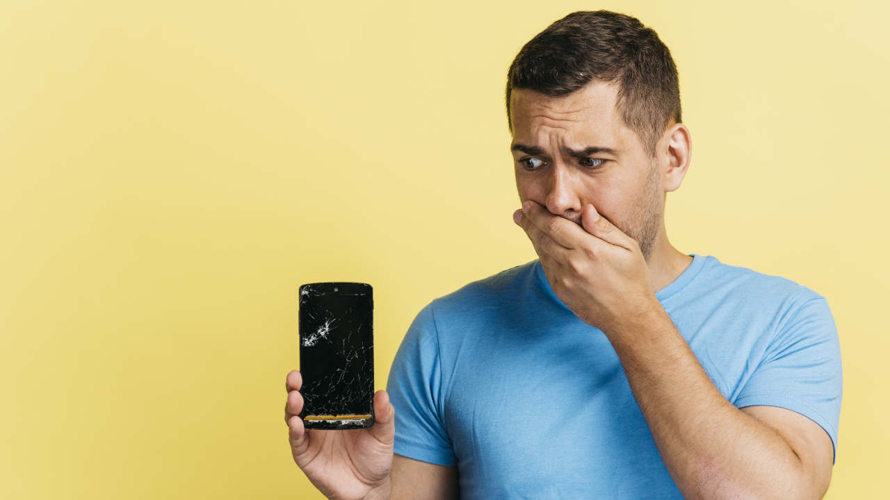 Homem com celular quebrado na mão