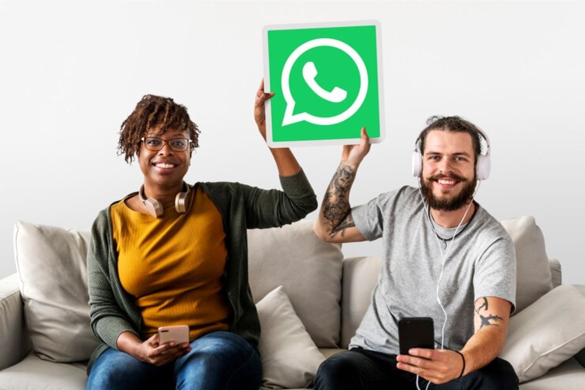 Um casal no sofá, eles conversam e seguram um símbolo do Whatsapp ganha novas funções