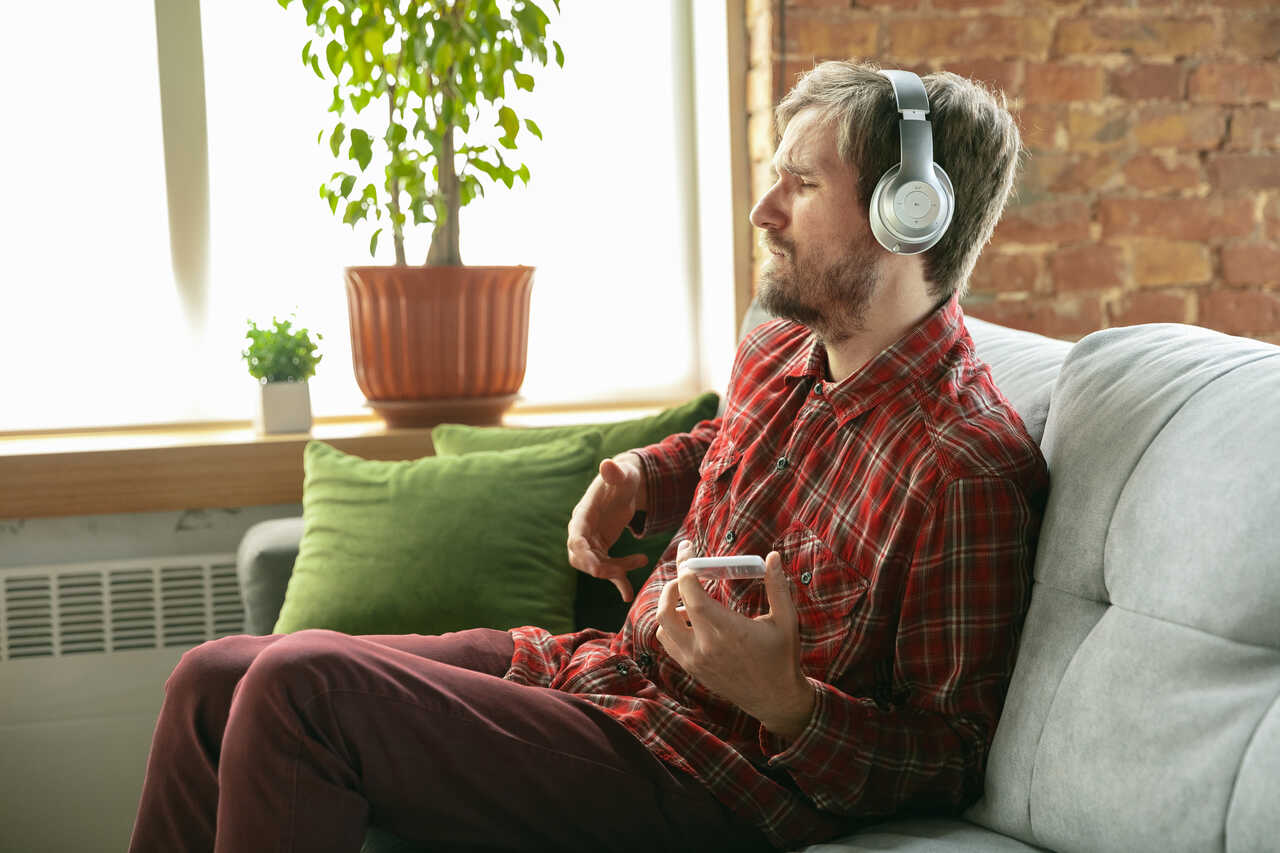 Homem escutando música no celular com fones de ouvido simula tocar guitarra 