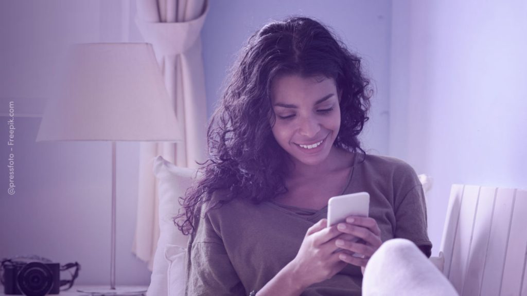 Moça sentada com seu celular nas mãos