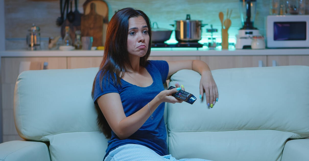 Mulher assistindo TV no sofá da sala