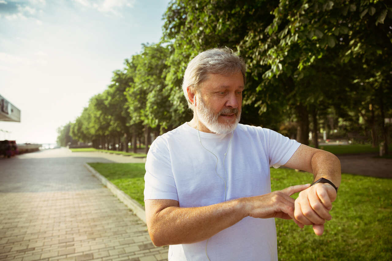 Homem idoso caminhando enquanto confere smartwatch no pulso