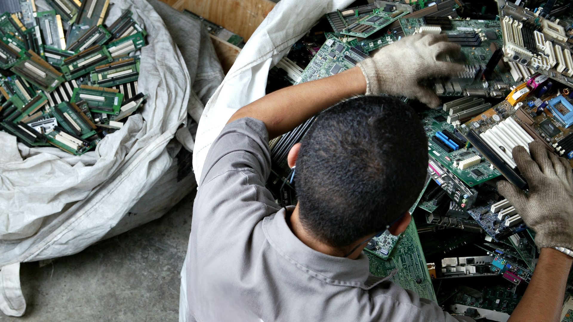 Homem manuseando pilha de lixo eletrônico