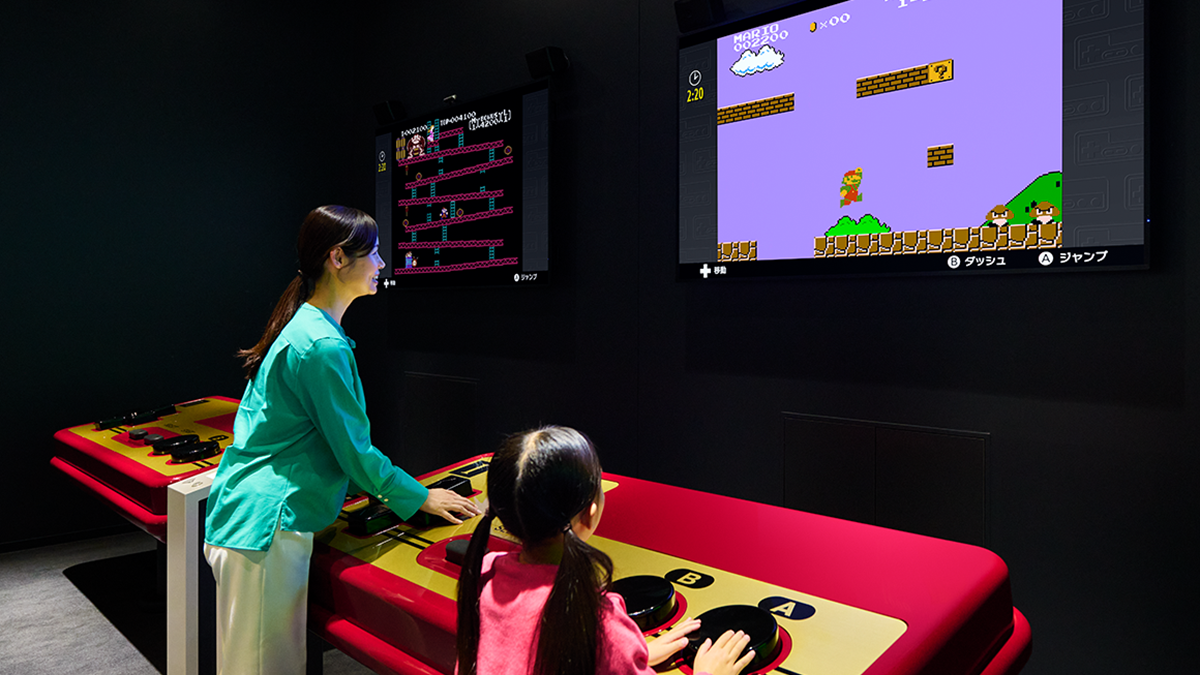 Mulher e criança jogando em console gigante dentro de Museu da Nintendo no Japão