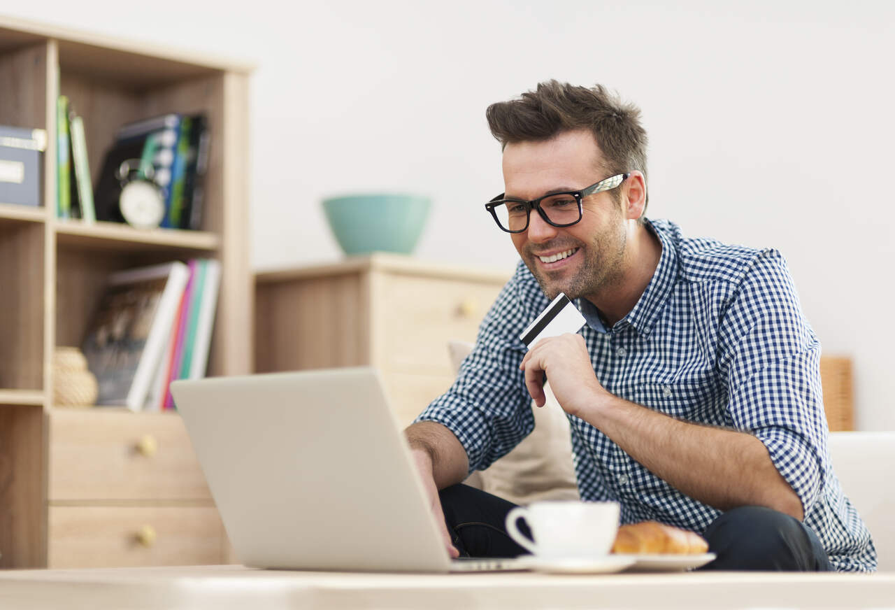 homem sorridente fazendo compras online 