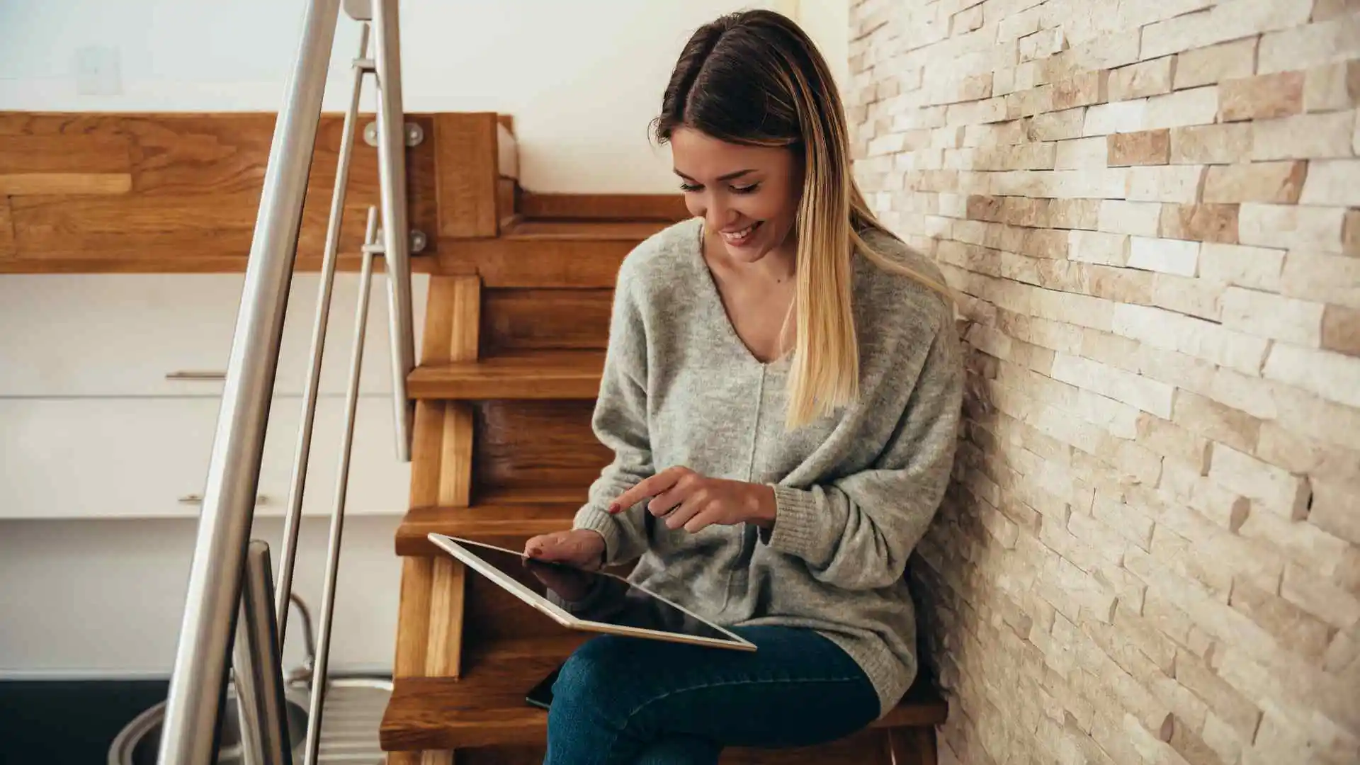 Mulher sentada na escada mexendo em uma tablet